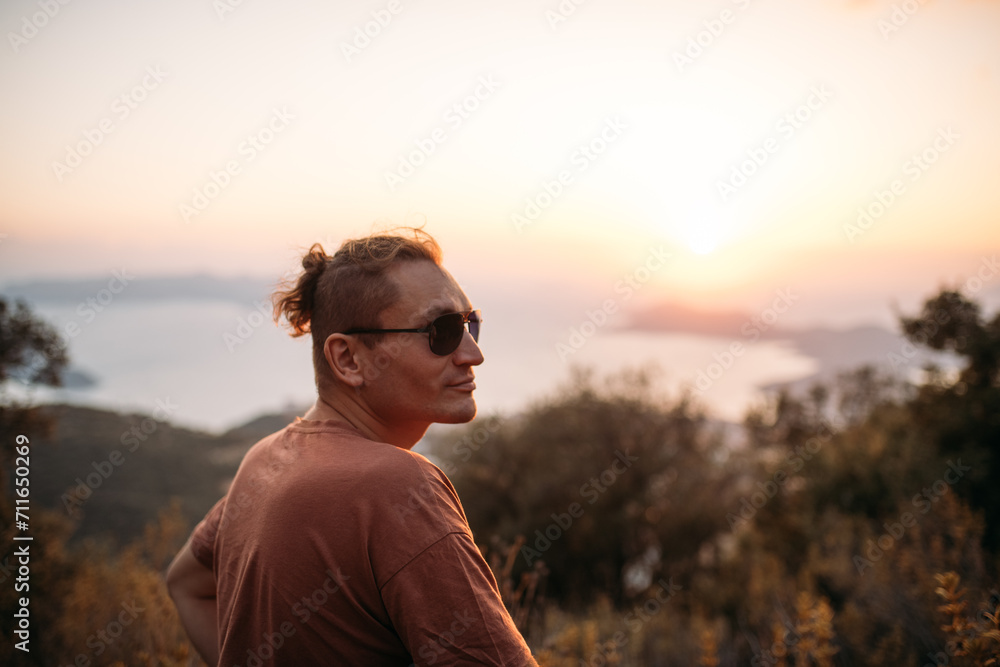 A male tourist on a picturesque viewpoint at sunset by the sea.