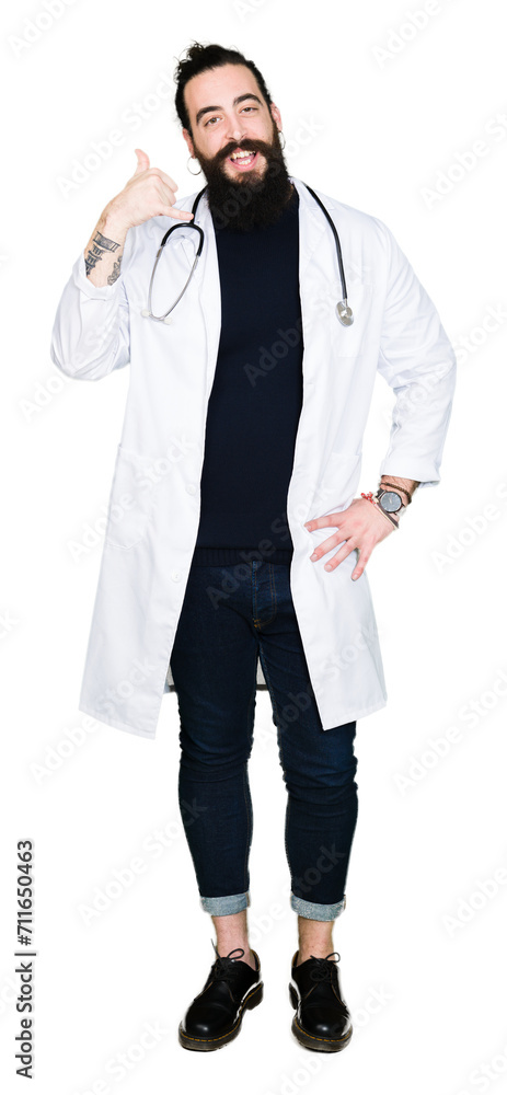 Doctor with long hair wearing medical coat and stethoscope smiling doing phone gesture with hand and fingers like talking on the telephone. Communicating concepts. Doctor with long hair wearing medical coat and stethoscope smiling doing phone gesture with hand and fingers like talking on the telephone. Communicating concepts.