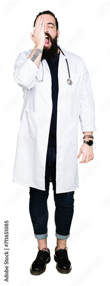 Doctor with long hair wearing medical coat and stethoscope Yawning tired covering half face, eye and mouth with hand. Face hurts in pain. Doctor with long hair wearing medical coat and stethoscope Yawning tired covering half face, eye and mouth with hand. Face hurts in pain.