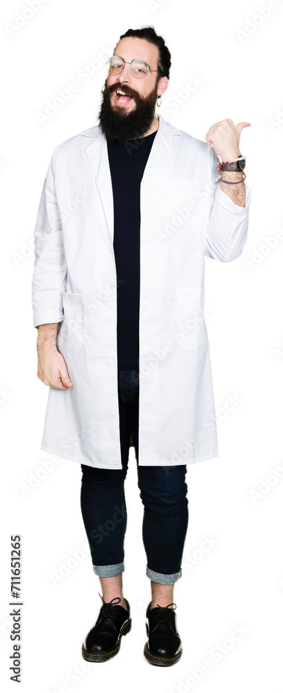 Doctor therapist man with long hair and bear wearing white coat smiling with happy face looking and pointing to the side with thumb up. Doctor therapist man with long hair and bear wearing white coat smiling with happy face looking and pointing to the side with thumb up.