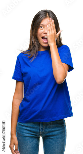 Young asian woman over isolated background covering one eye with hand with confident smile on face and surprise emotion.