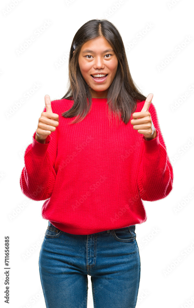 Young asian woman wearing winter sweater over isolated background success sign doing positive gesture with hand, thumbs up smiling and happy. Looking at the camera with cheerful expression. Young asian woman wearing winter sweater over isolated background success sign doing positive gesture with hand, thumbs up smiling and happy. Looking at the camera with cheerful expression.