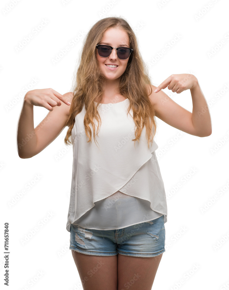 Young blonde woman wearing sunglasses looking confident with smile on face, pointing oneself with fingers proud and happy. Young blonde woman wearing sunglasses looking confident with smile on face, pointing oneself with fingers proud and happy.
