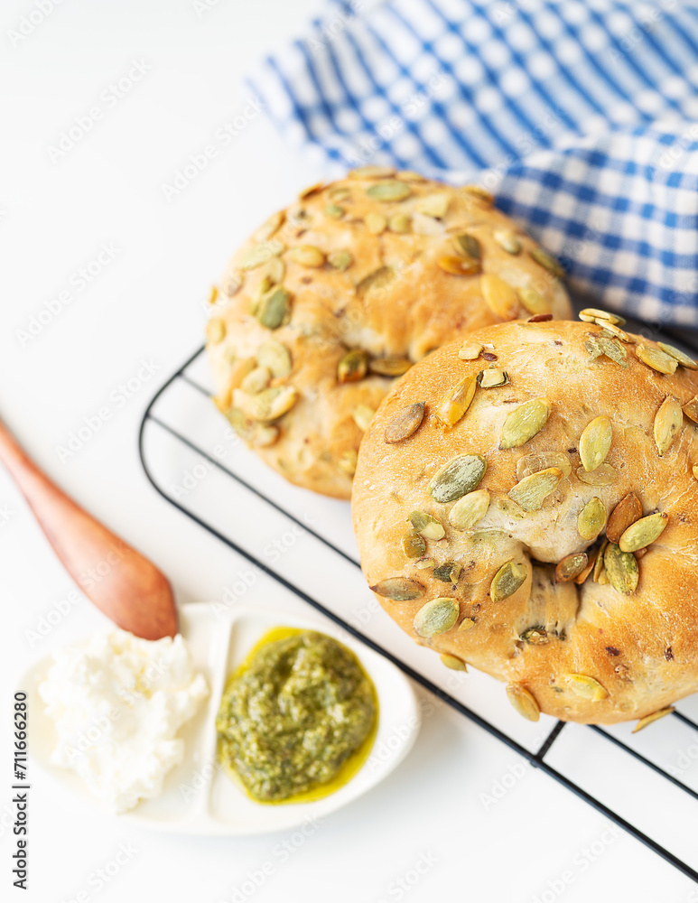 Fresh pumpkin seed bread with pesto and cream cheese on wire rack, blue checkered cloth background. Fresh pumpkin seed bread with pesto and cream cheese on wire rack, blue checkered cloth background.