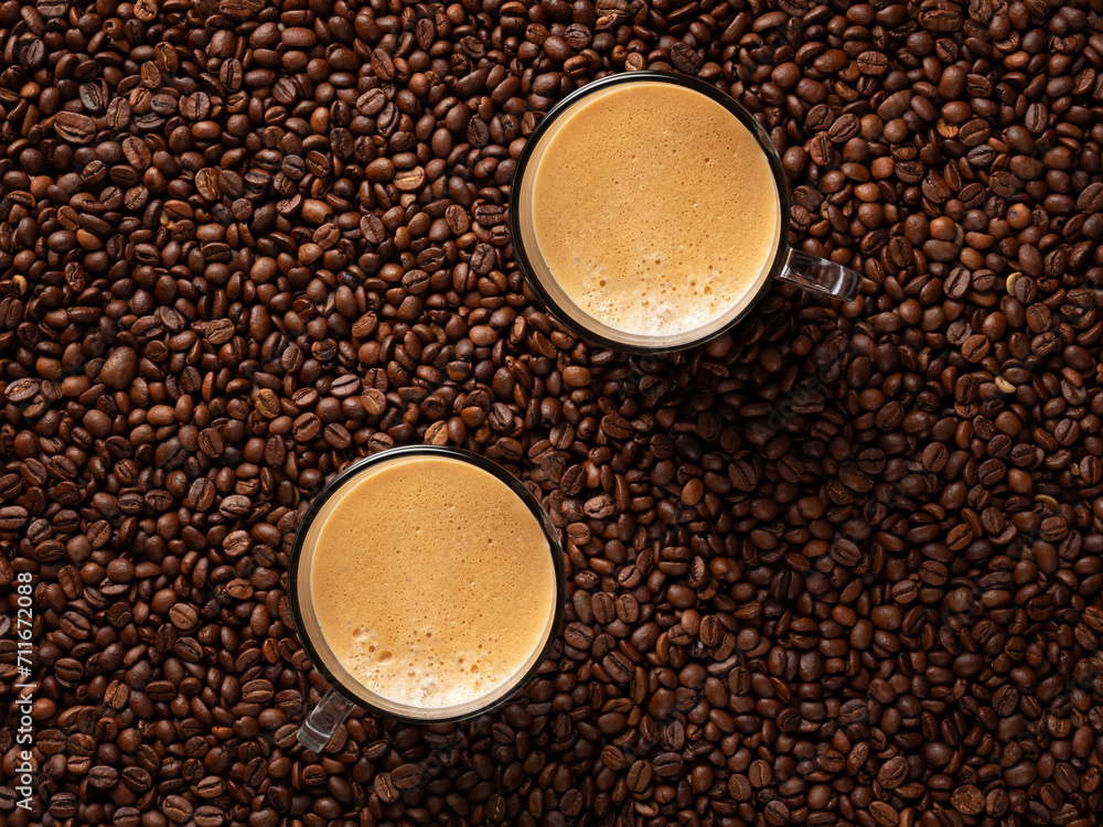 Top view of a lot of roasted coffee beans and two glass cups with fresh espresso coffee. Top view of a lot of roasted coffee beans and two glass cups with fresh espresso coffee.
