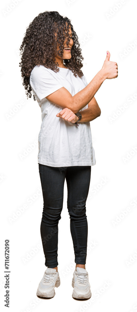 Young beautiful woman with curly hair wearing white t-shirt Looking proud, smiling doing thumbs up gesture to the side Young beautiful woman with curly hair wearing white t-shirt Looking proud, smiling doing thumbs up gesture to the side