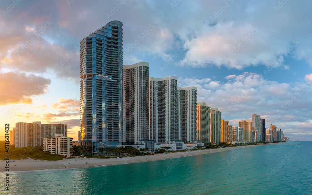 Naklejka premium Evening landscape of sandy beachfront in Sunny Isles Beach city with luxurious highrise hotels and condo buildings on Atlantic ocean shore. American tourism infrastructure in southern Florida