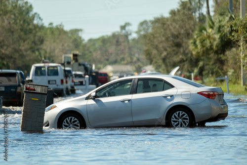 Hurricane flooded street with broken car in surrounded with water Florida residential area. Consequences of natural disaster