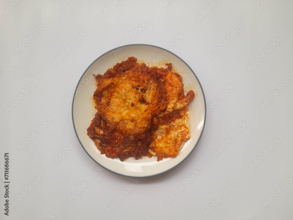 food fried egg (telur ceplok) balado with chili sauce on a plate on a white background. background concept of healthy food, food recipe, dish, meal, cuisine, ingredient, gourmet,breakfast, lunch, cook food fried egg (telur ceplok) balado with chili sauce on a plate on a white background. background concept of healthy food, food recipe, dish, meal, cuisine, ingredient, gourmet,breakfast, lunch, cook