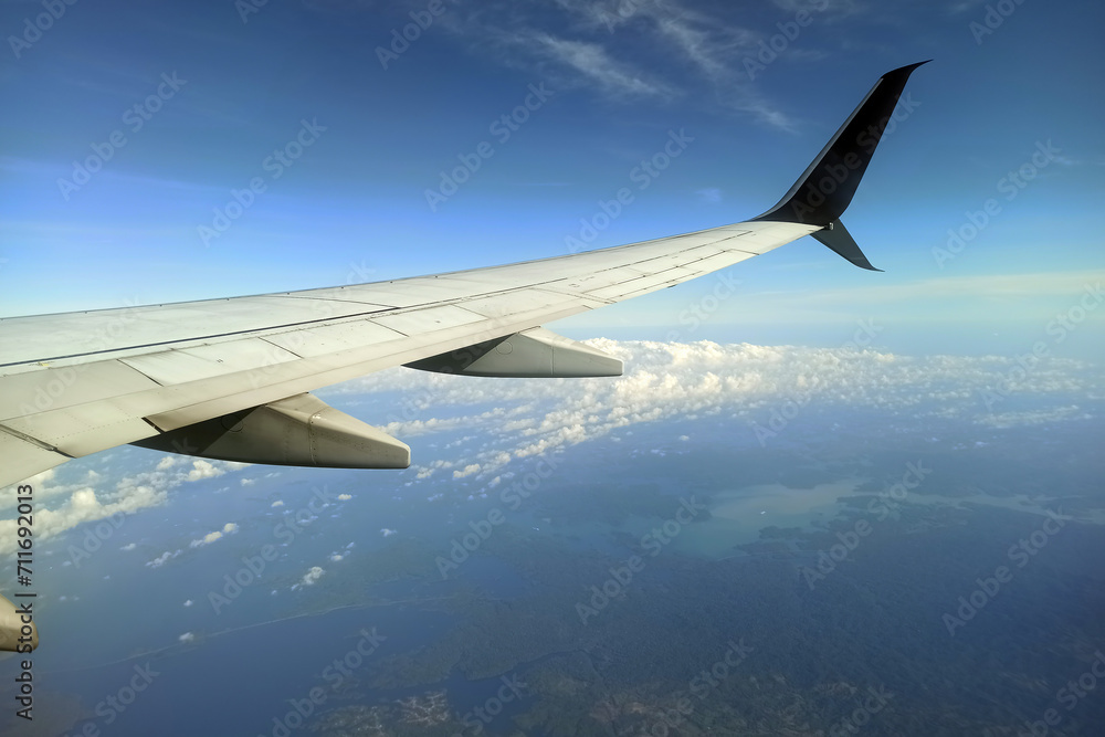 Obraz premium View through airplane window of commercial jet plane wing flying high in the sky. Air travelling concept