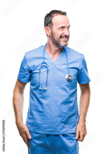 Middle age hoary senior doctor man wearing medical uniform over isolated background looking away to side with smile on face, natural expression. Laughing confident. © Krakenimages.com