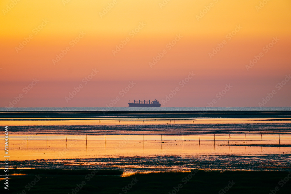 Serene Sunset Seascape with Distant Cargo Ship