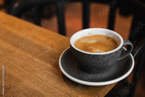 Cup of black coffee on the edge of a wooden table in a cafe coffee-shop with copy space