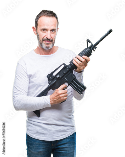 Middle age senior hoary criminal man holding gun weapon over isolated background with a confident expression on smart face thinking serious