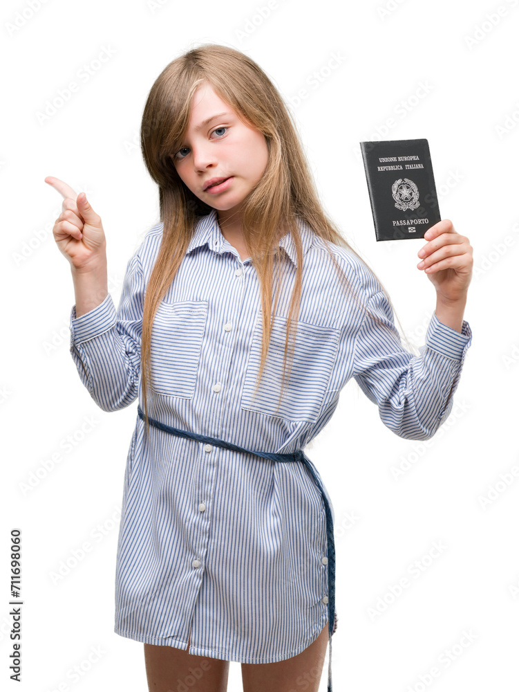 Obraz premium Young blonde toddler holding italian passport very happy pointing with hand and finger to the side