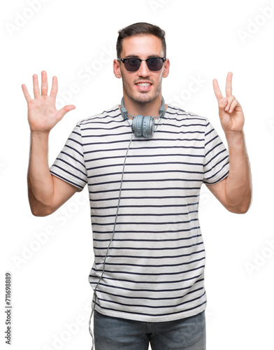 Handsome young man wearing headphones showing and pointing up with fingers number seven while smiling confident and happy.