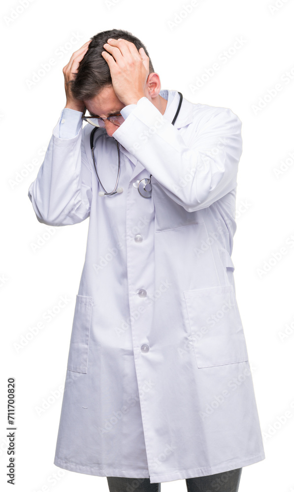 Handsome young doctor man suffering from headache desperate and stressed because pain and migraine. Hands on head. Handsome young doctor man suffering from headache desperate and stressed because pain and migraine. Hands on head.