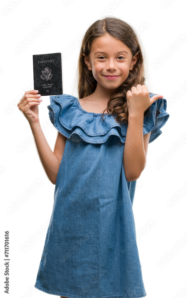 Brunette hispanic girl holding passport of United States of America pointing and showing with thumb up to the side with happy face smiling Brunette hispanic girl holding passport of United States of America pointing and showing with thumb up to the side with happy face smiling