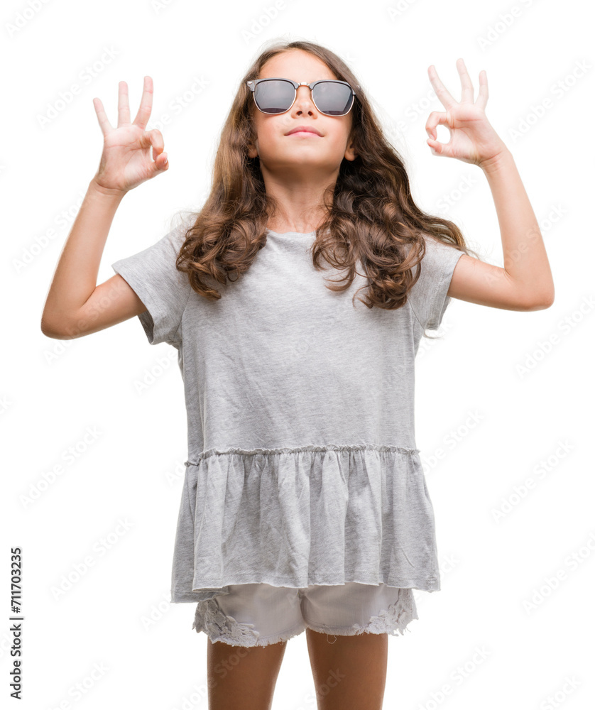 Brunette hispanic girl wearing sunglasses relax and smiling with eyes closed doing meditation gesture with fingers. Yoga concept. Brunette hispanic girl wearing sunglasses relax and smiling with eyes closed doing meditation gesture with fingers. Yoga concept.