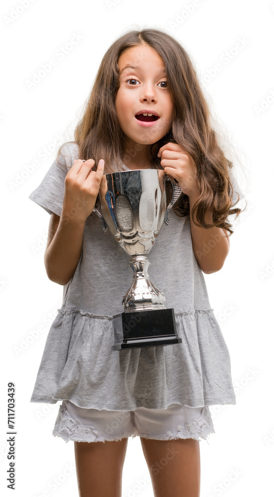 Brunette hispanic girl holding a trophy scared in shock with a surprise face, afraid and excited with fear expression Brunette hispanic girl holding a trophy scared in shock with a surprise face, afraid and excited with fear expression
