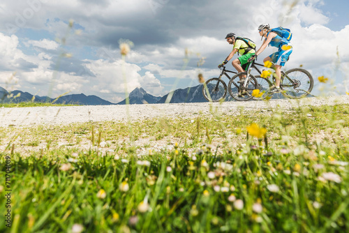 Paar fährt mit Mountainbike auf Schotterweg in den Bergen, Österreich photo