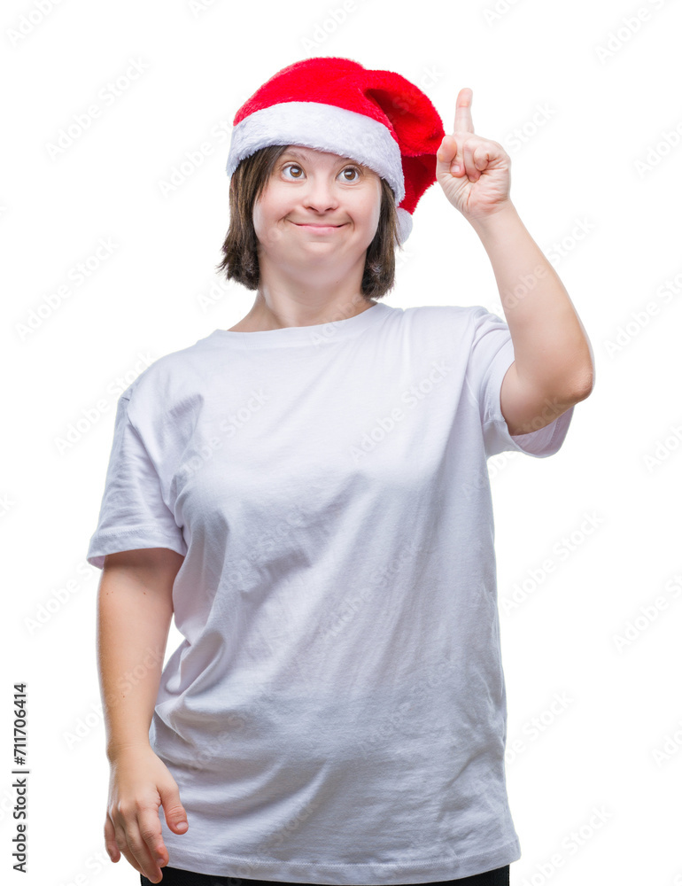 Young adult woman with down syndrome wearing christmas hat over isolated background pointing finger up with successful idea. Exited and happy. Number one. Young adult woman with down syndrome wearing christmas hat over isolated background pointing finger up with successful idea. Exited and happy. Number one.