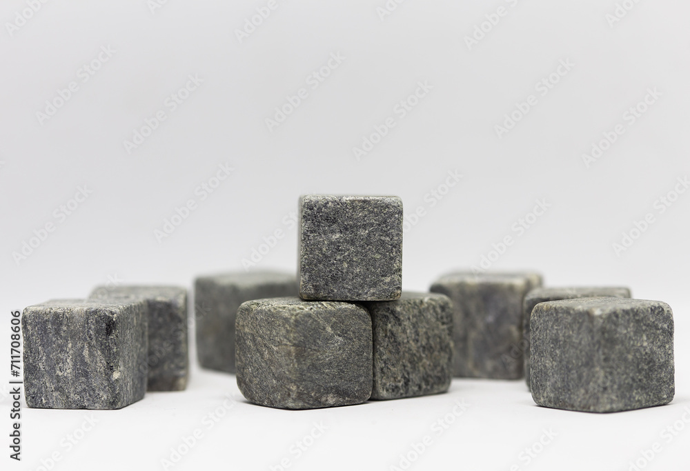 Stone whiskey cubes. A collection of grey, textured stone cubes arranged randomly against a white background. The cubes are of different sizes and stacked on top of each other. Stone whiskey cubes. A collection of grey, textured stone cubes arranged randomly against a white background. The cubes are of different sizes and stacked on top of each other.