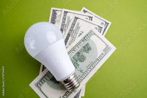 Light bulb and dollars on a colored background. Increasing cost of electricity for residential and business users, high electricity bills and rising electricity prices concept