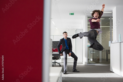 zwei Männer im Businessoutfit springen vor Freude im Büro, München, Deutschland
