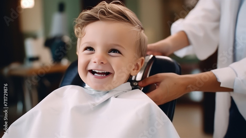 Portrait of happy smiling modern toddler child sitting in barber chair getting first haircut. Barbershop for children, beauty salon, copy space.