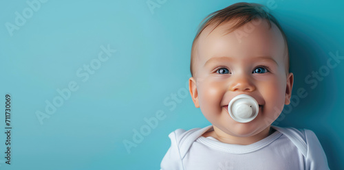 Smiling baby boy with pacifier portrait on flat blue background with copy space. Banner template with infant child smile. photo