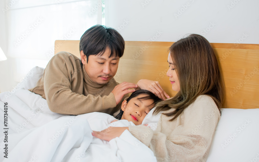 Three people of Asian family, father, mother, little daughter lying down, sleeping on bed in bedroom at cozy home with happiness, warmth. Residence, Kid, Housing, Healthcare Concept. Three people of Asian family, father, mother, little daughter lying down, sleeping on bed in bedroom at cozy home with happiness, warmth. Residence, Kid, Housing, Healthcare Concept.