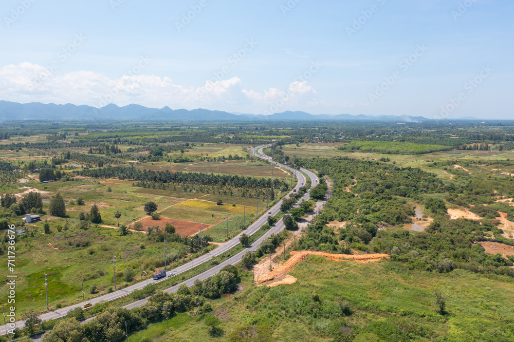 Aerial view of cars driving on curved, zigzag curve road or street on mountain hill with green natural forest trees in rural city town of Songkhla, Thailand. Transportation.