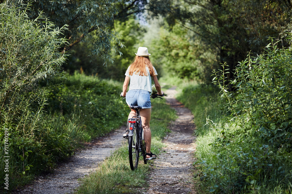 Portrait of fitness woman dressed casual clothes riding a bicycle on the out-of-town road. Active sporty people concept.