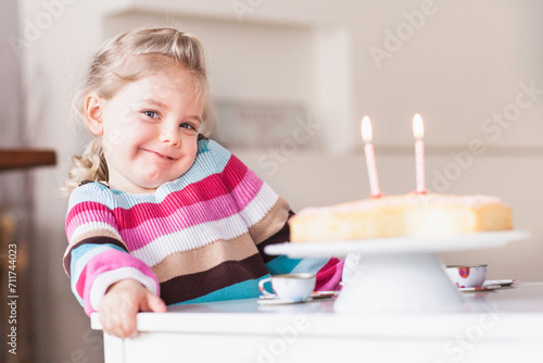 Young girl looking into the camera before blowing out the candles on her birthday cake. Munich, Germany photo
