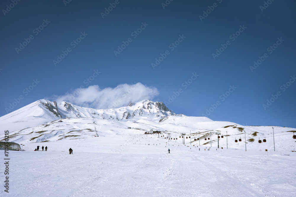 Snow-covered mountain with ski slope and lifts in a European ski resort against a blue cloudy sky. Nature, beautiful views. Vacation. Travel content Snow-covered mountain with ski slope and lifts in a European ski resort against a blue cloudy sky. Nature, beautiful views. Vacation. Travel content