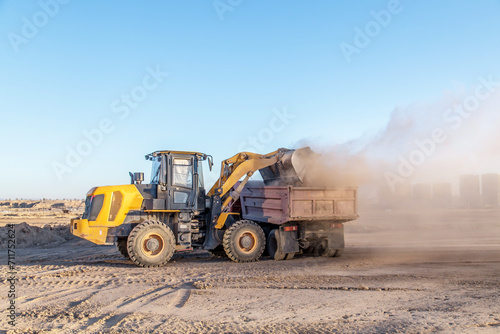 Tractor loader loads a truck on a construction site.Dust on a construction site.Blur.