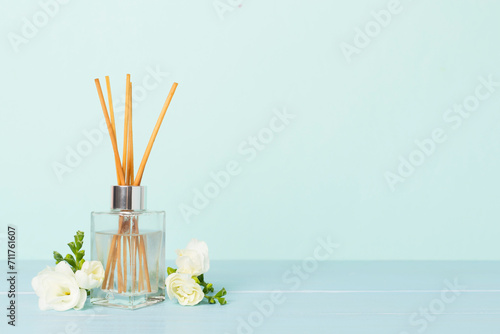 Reed aroma diffuser with freesia flower on wooden table photo
