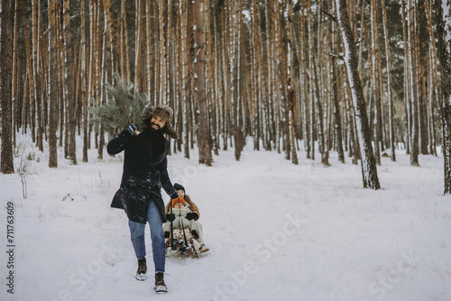 father and children on a sleigh ride through the forest in search of a Christmas tree