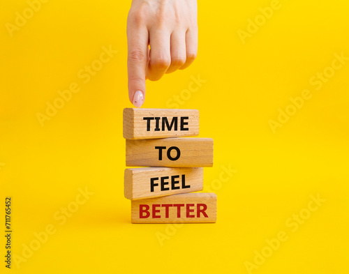 Time to feel better symbol. Wooden blocks with words Time to feel better. Businessman hand. Beautiful yellow background. Medicine and Time to feel better concept. Copy space. photo