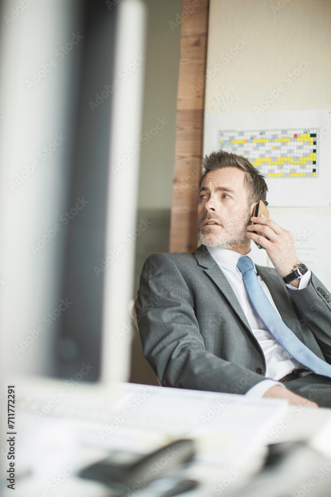 Business man talking on his smart phone while sitting in his office. Business man talking on his smart phone while sitting in his office.