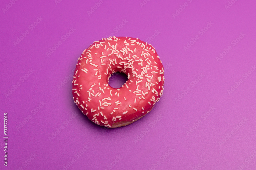 close up of pink donut against plain purple backdrop close up of pink donut against plain purple backdrop