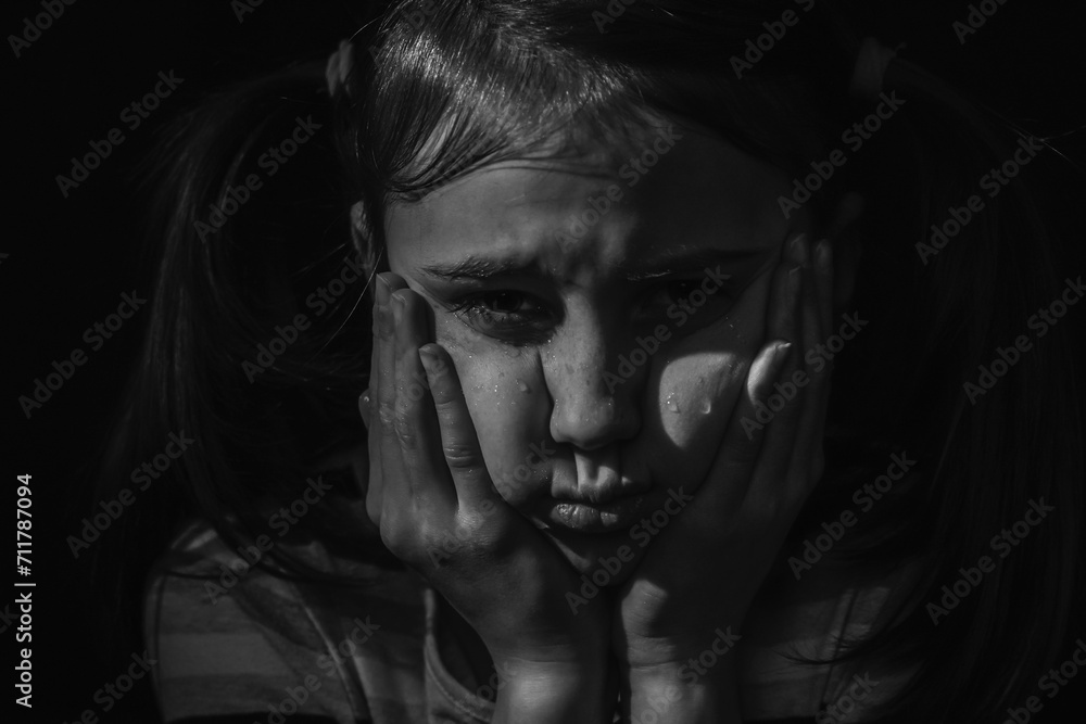 Cute little sad offended child girl is crying on a black background. Black and white image. Cute little sad offended child girl is crying on a black background. Black and white image.