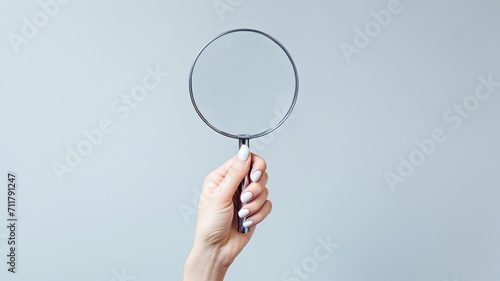 a woman holding a magnifying glass in a closeup shot against a grey background, a composition in a minimalist modern style, highlighting the simplicity and focus.