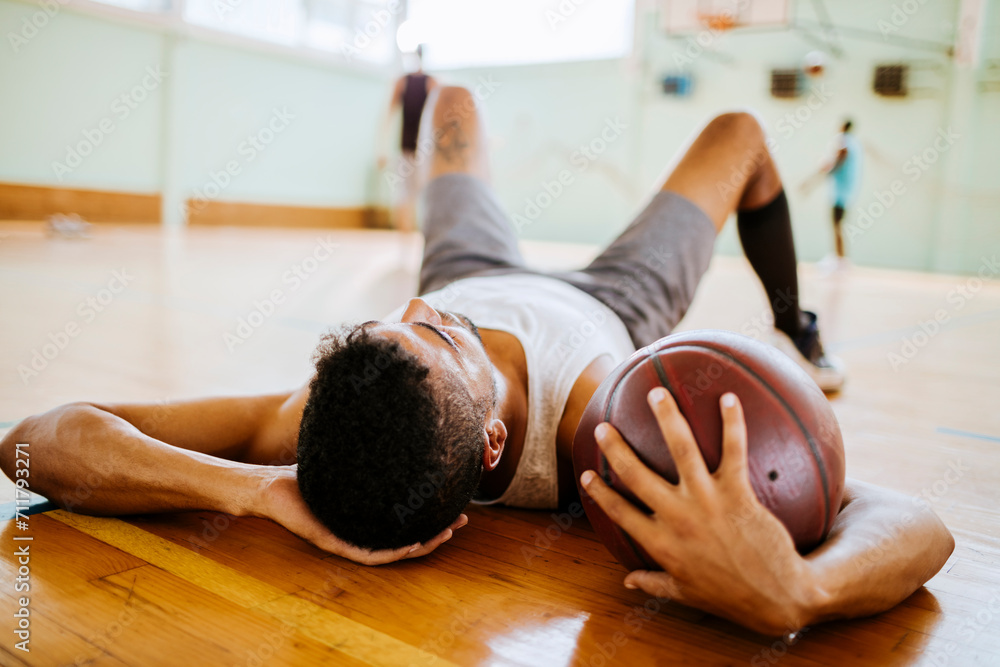 © Marko Geber - Young man taking a break from playing basketball in an indoor basketball gym © Marko Geber - Young man taking a break from playing basketball in an indoor basketball gym