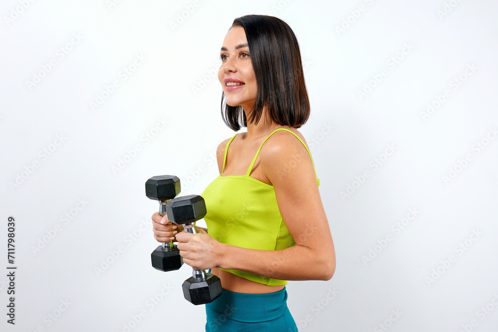 Athletic female fitness trainer in sexy yellow top holding dumbbells