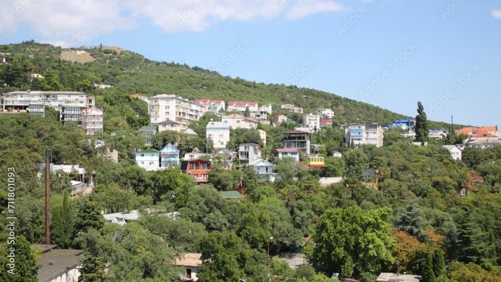 Cableway and buildings among trees in small town at summer day Cableway and buildings among trees in small town at summer day