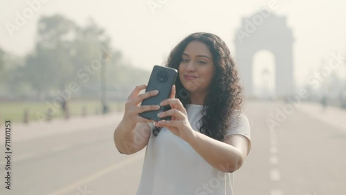 Indian Girl with Curly Hair Taking Selfie at India Gate photo