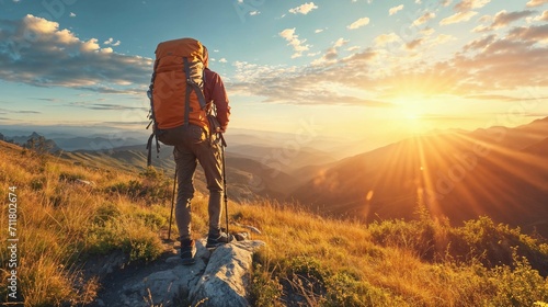 Hiker with a large backpack standing on a mountain trail at sunrise, overlooking a range of mountains with the sun casting golden light across the landscape