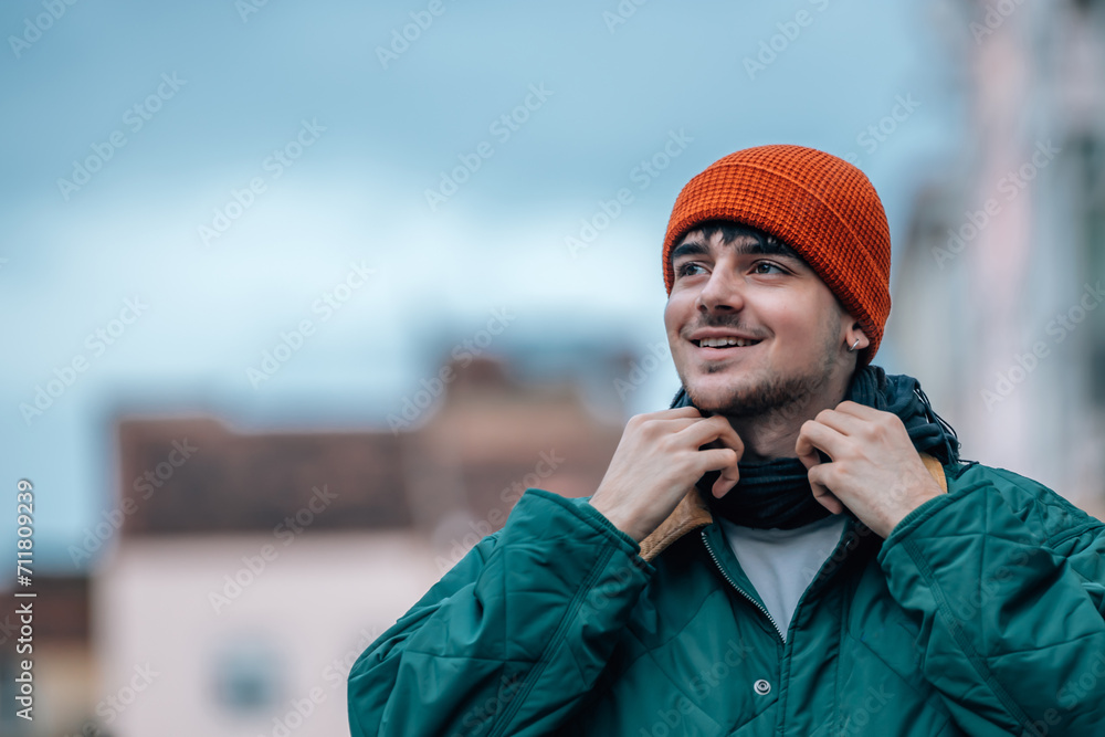 portrait of young man on the street in winter warm and wearing a hat